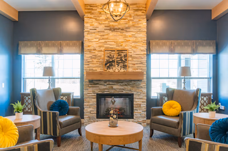 Lounge at Elysian Senior Homes of Duluth featuring a stone fireplace, blue walls, and seating.