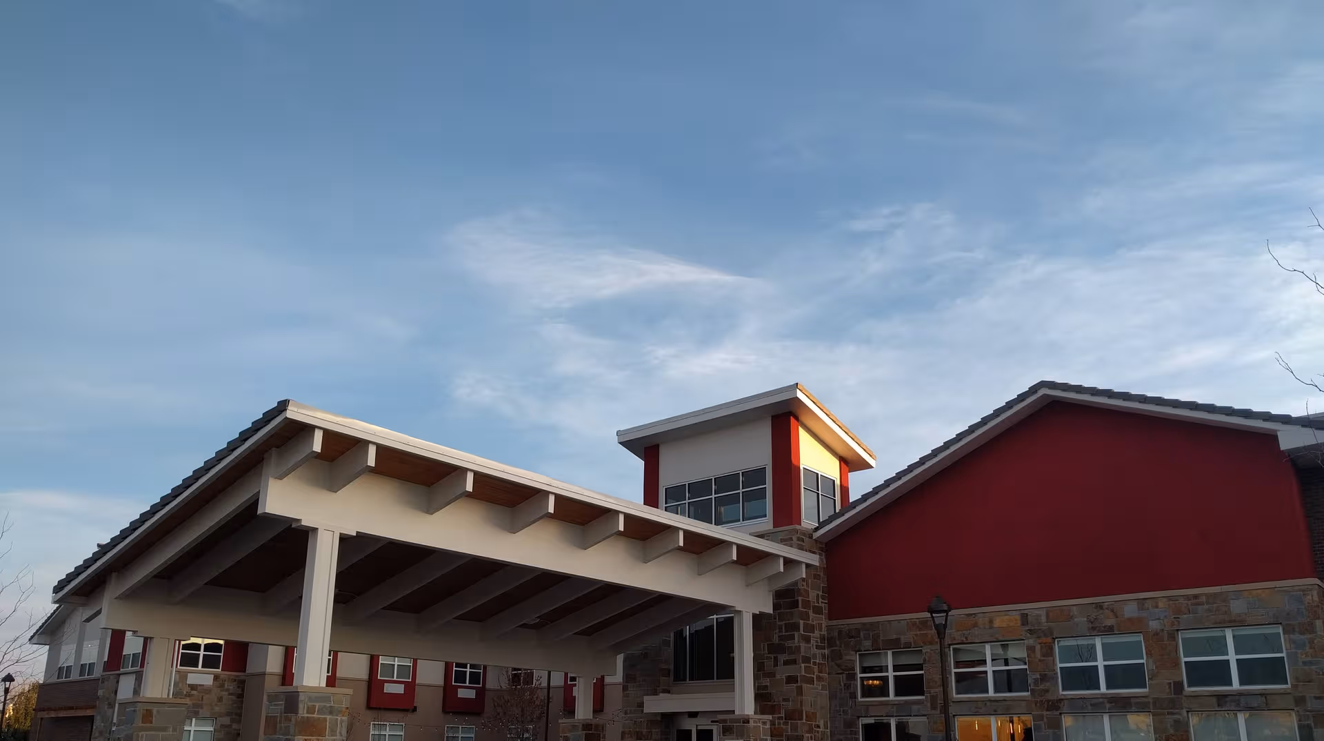 Exterior view of a red and stone senior living facility with a covered entrance.