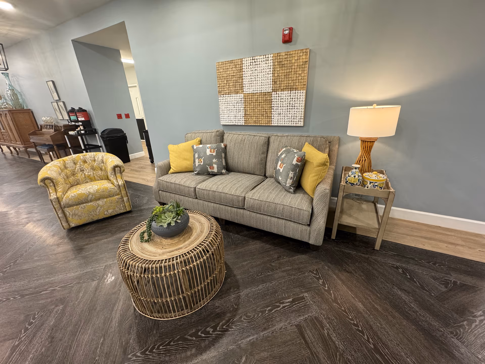 A furnished lounge area with sofa, armchair, coffee table, and wall art.