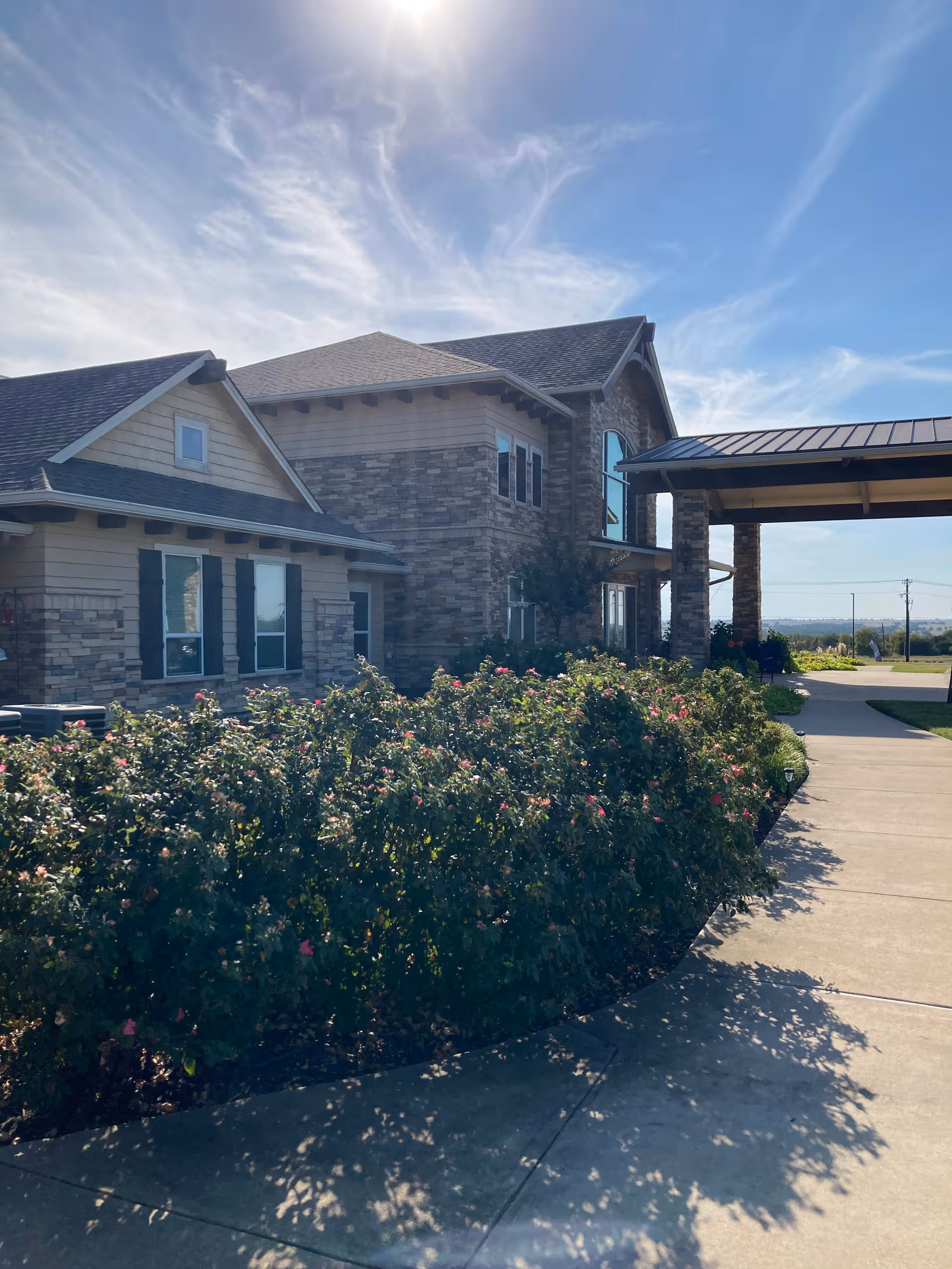 Bristol Park at Cleburne senior living facility exterior with a covered entrance and landscaped shrubs.