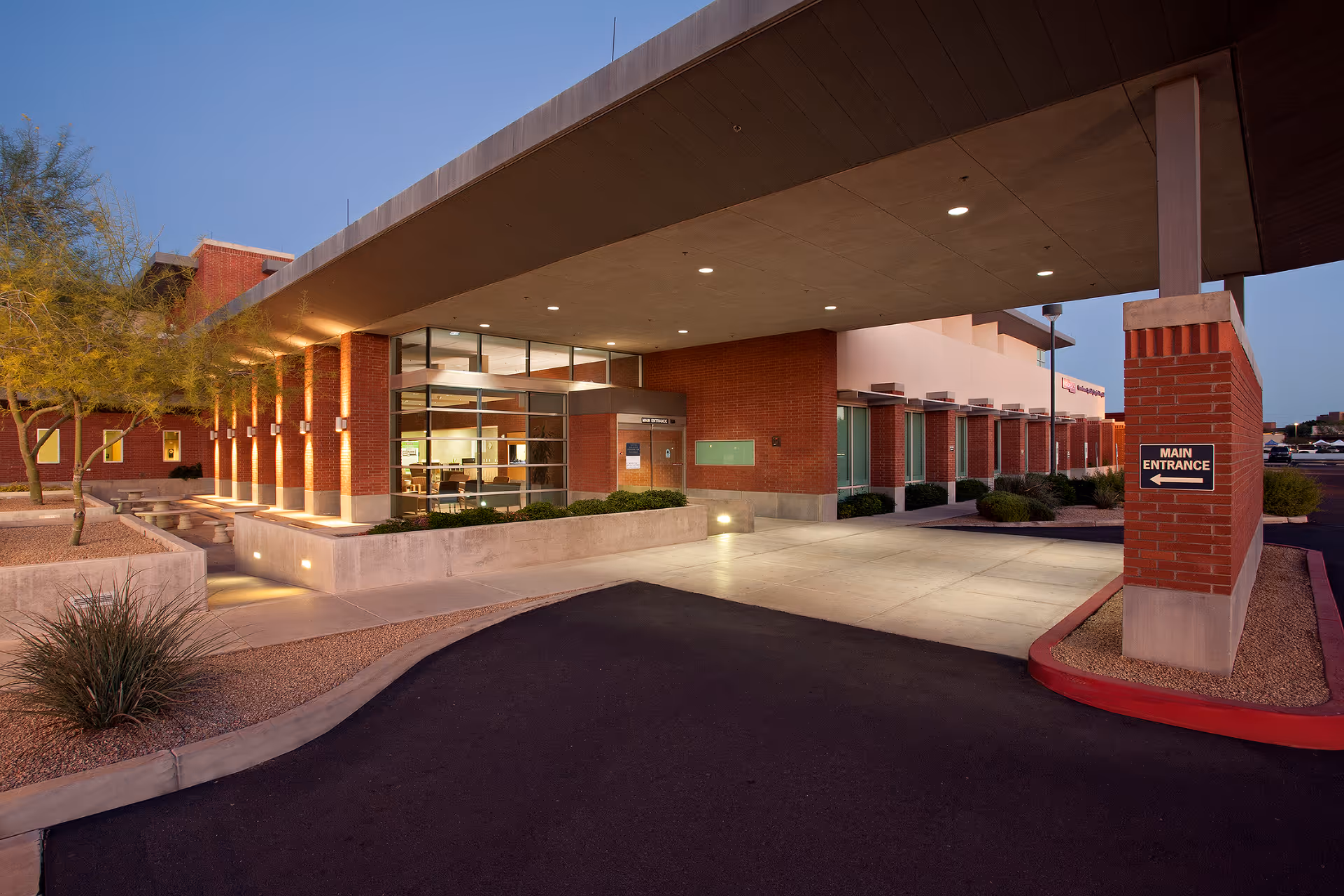 Exterior view of a brick hospital with a covered entrance and main entrance sign.