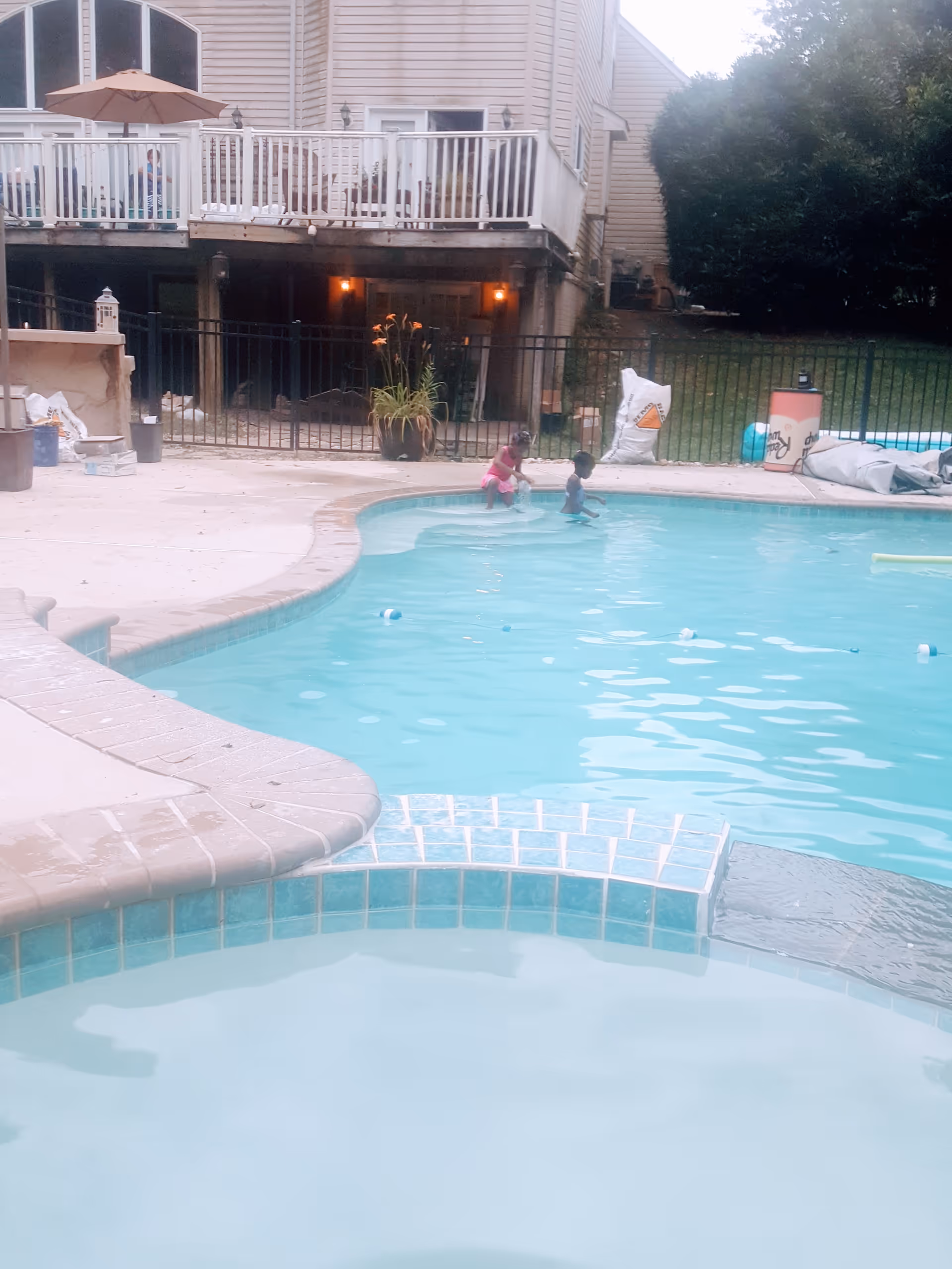 Outdoor pool area of a residential building with two children playing in water