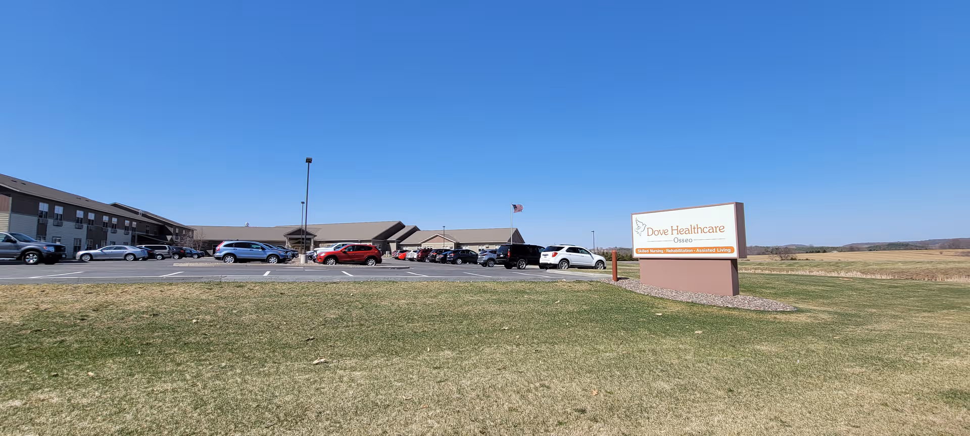 Exterior view of Dove Healthcare – Osseo Assisted Living with a parking lot in front.
