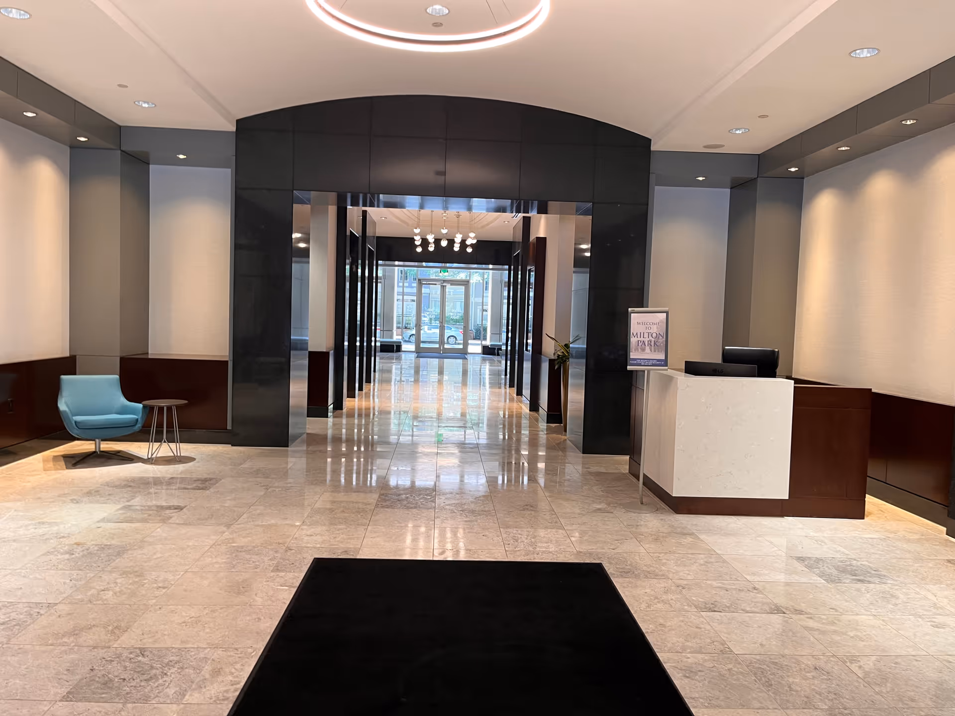 Senior living facility lobby with a reception desk, black archways, and blue seating.
