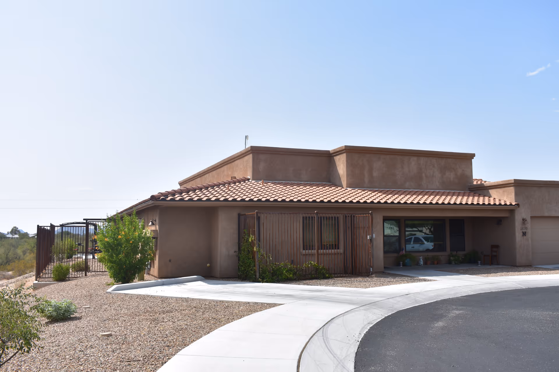 Single story tan assisted living building with red tile roof and desert landscaping.
