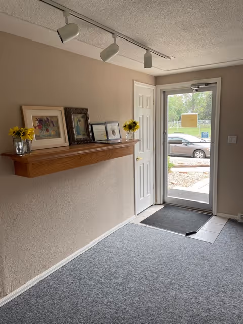 Interior entryway with a shelf displaying framed photos and yellow flowers.