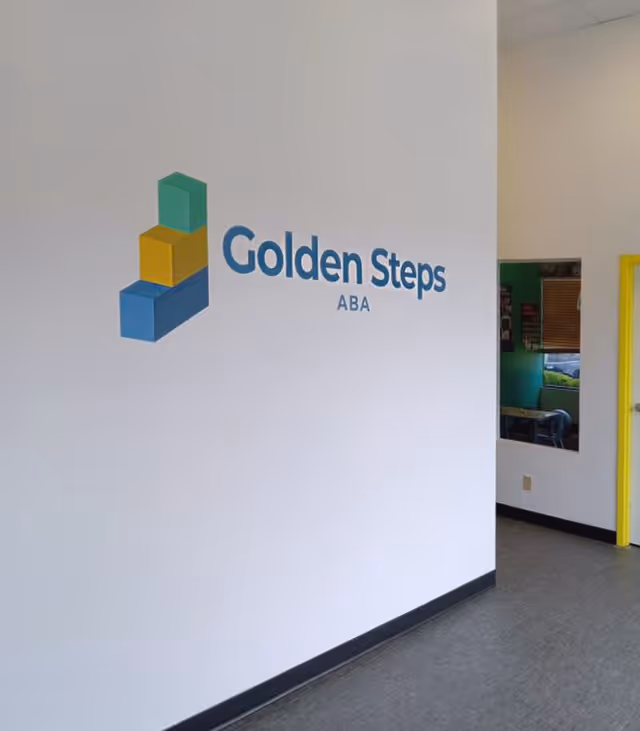 White interior wall with Golden Steps ABA logo and a doorway to the right.
