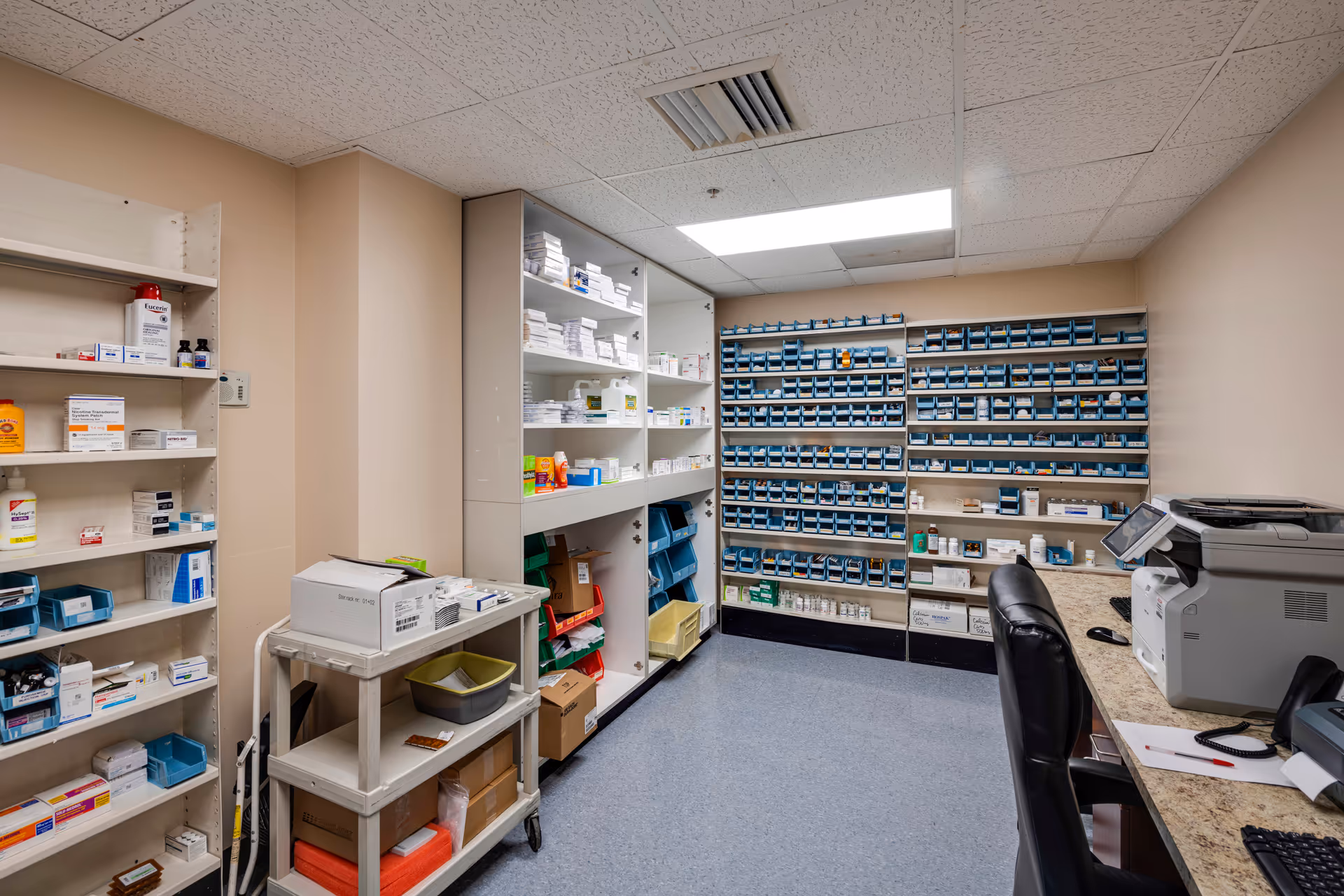 Interior medication room with numerous shelves of medications, a counter, and medical equipment.