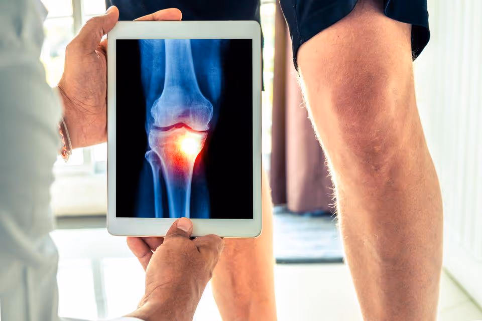 Medical staff shows tablet displaying a knee X-ray during an indoor orthopedic consultation.