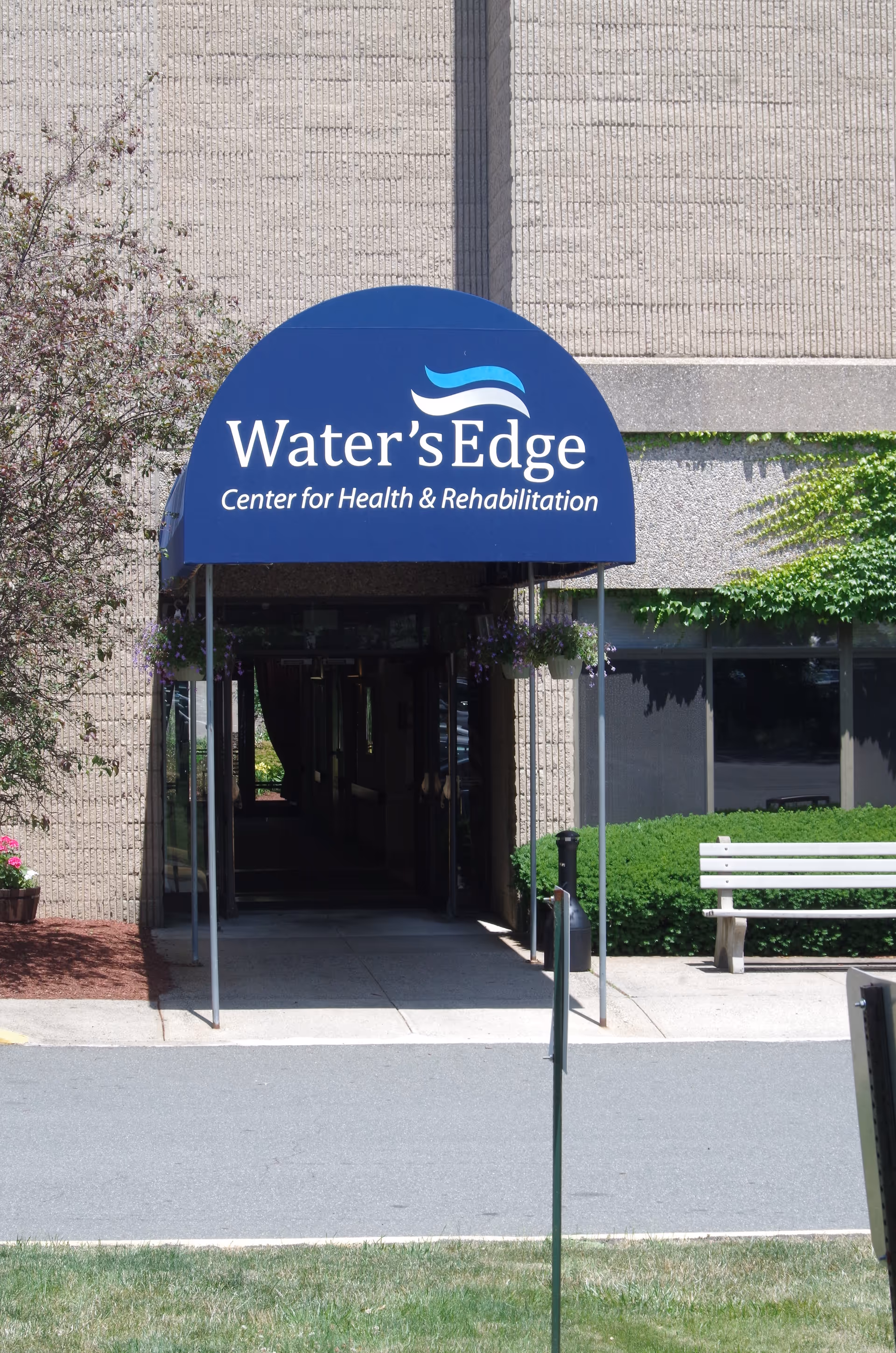Blue curved awning with Water's Edge sign over entrance to health center