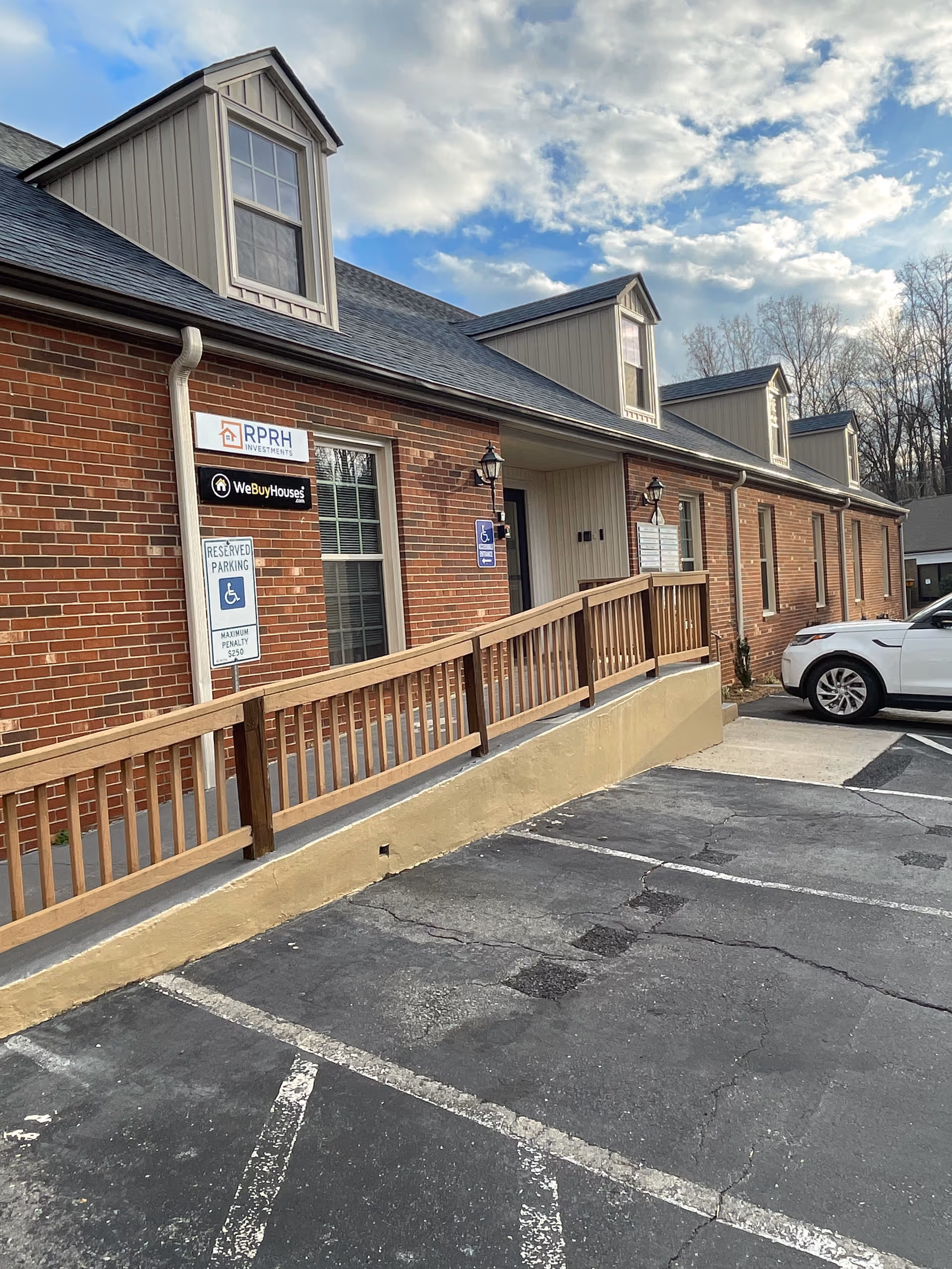 Brick exterior of an emergency training facility with ramps, parked car, and handicap signs.
