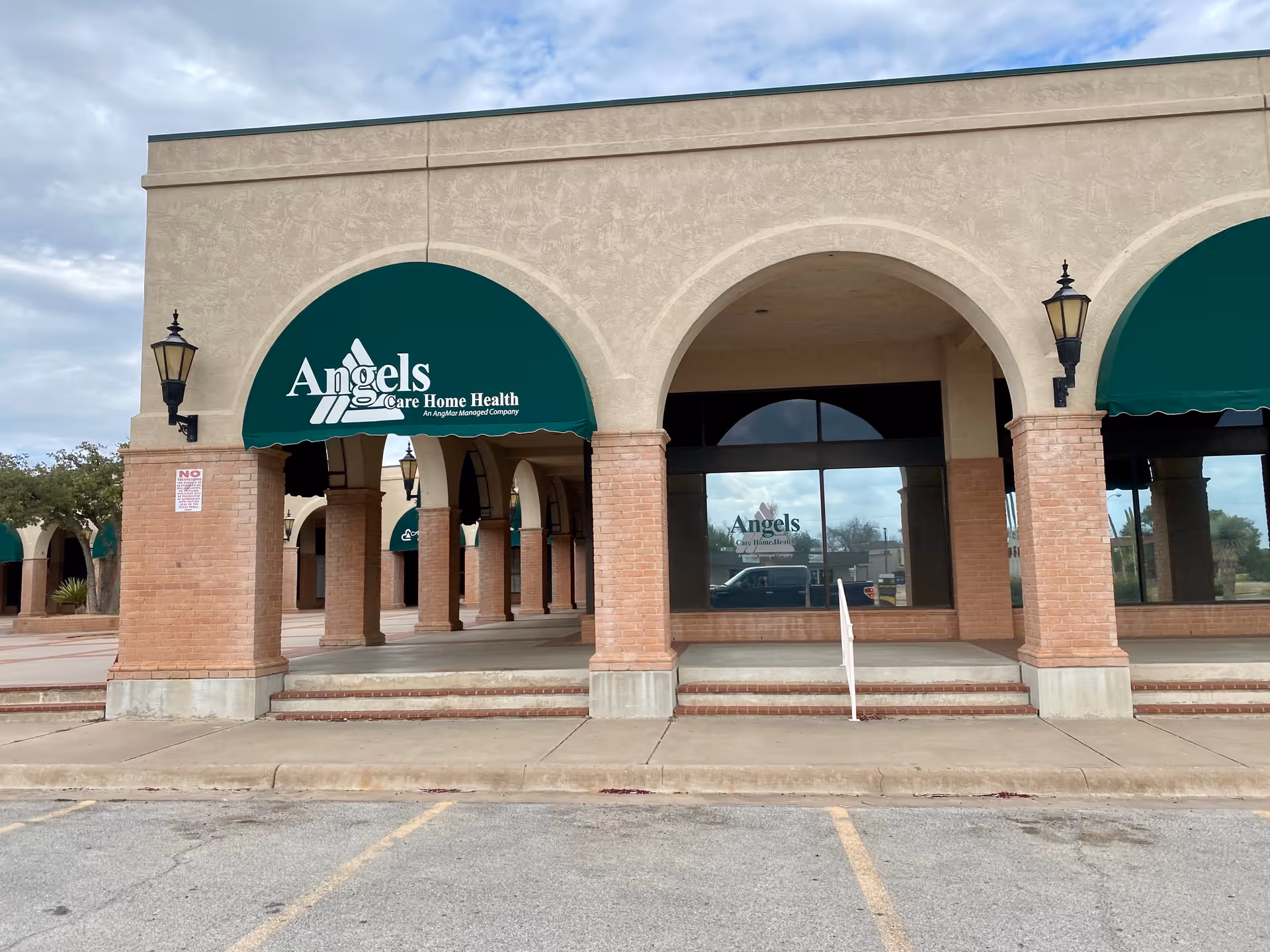 Exterior view of Angels Care Home Health storefront with arches, brick columns, and green awnings.