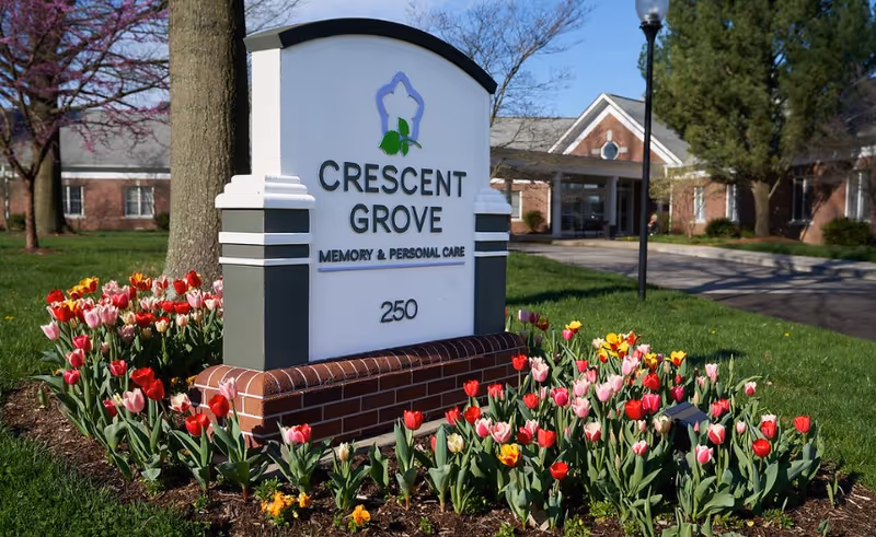 A sign reading Crescent Grove Memory & Personal Care at the facility entrance, surrounded by tulips.