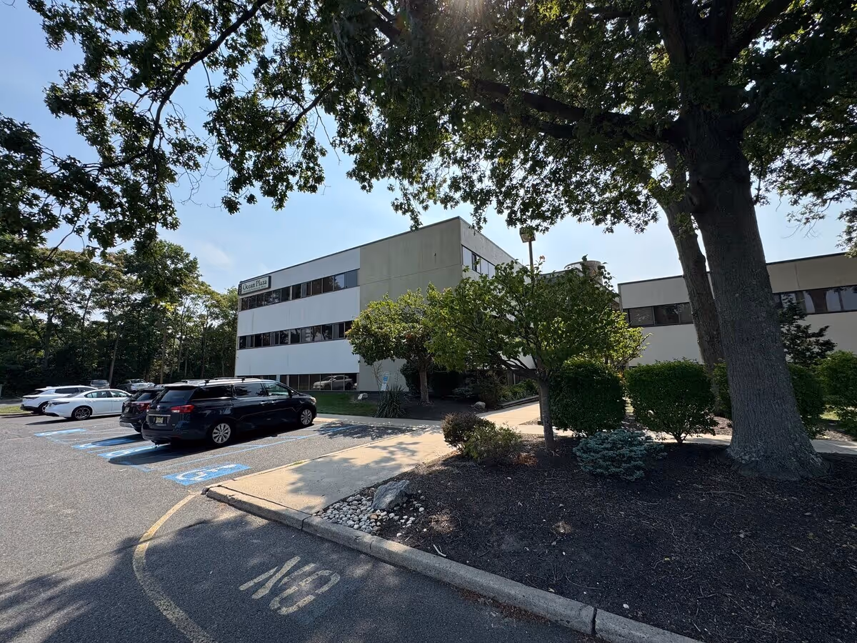 Exterior view of a two-story healthcare facility with a parking lot and trees