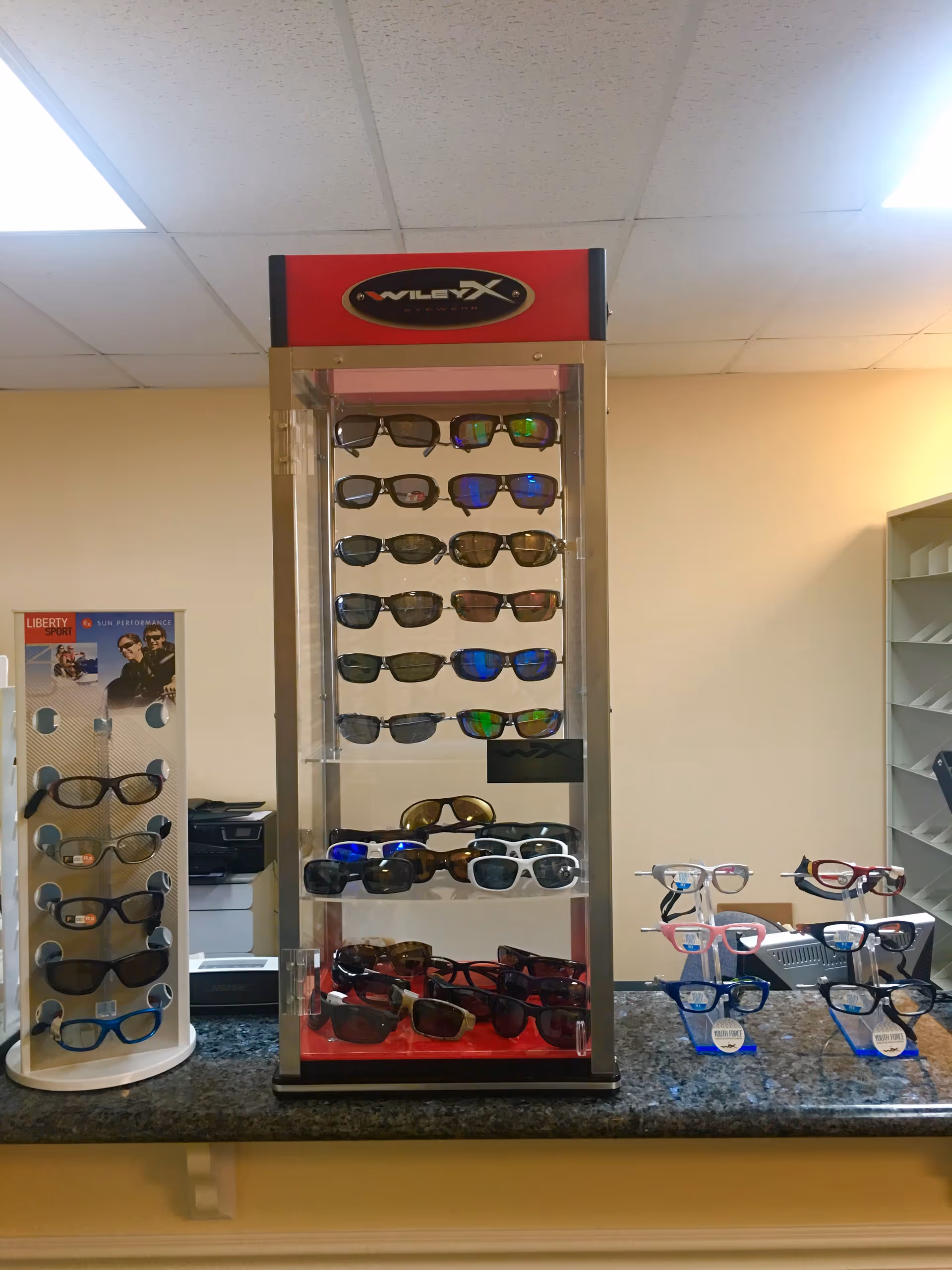 Interior at Silas Eye Care reception shows a tall sunglasses display with multiple eyewear racks.