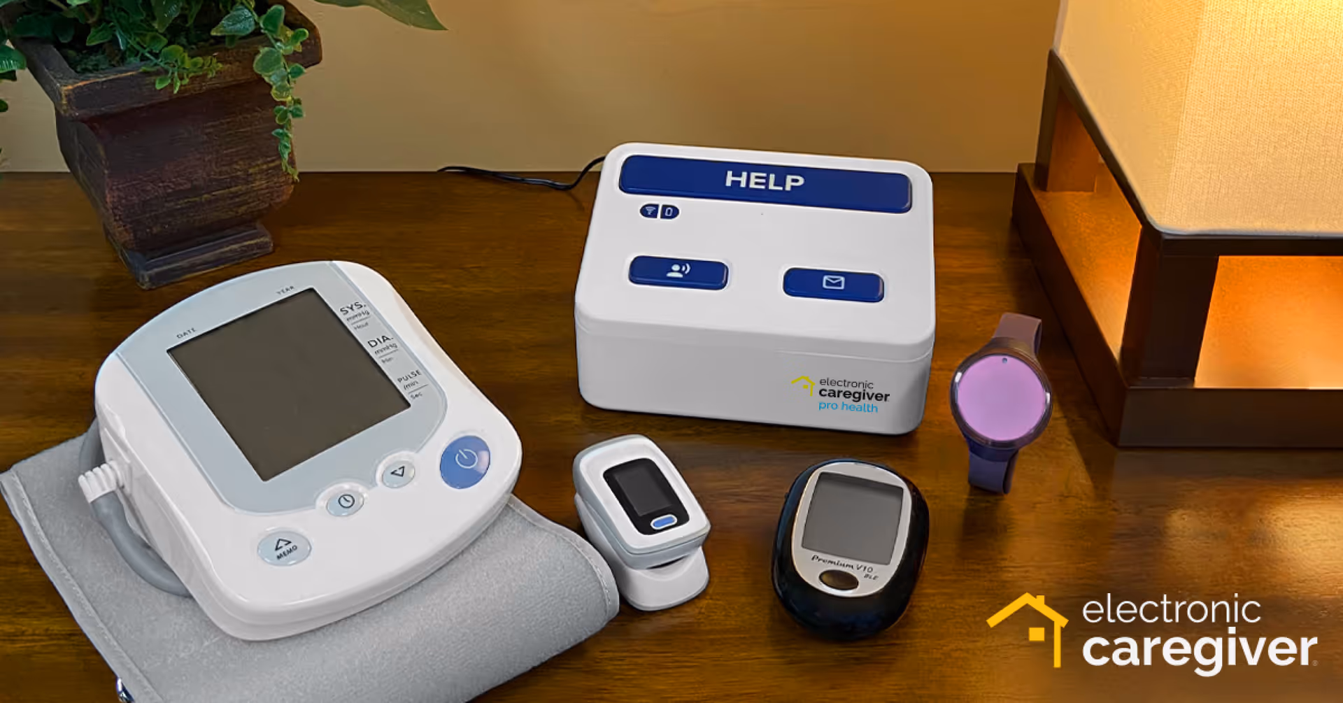 Medical monitoring devices on a wooden table, including a HELP unit and Electronic Caregiver branding.