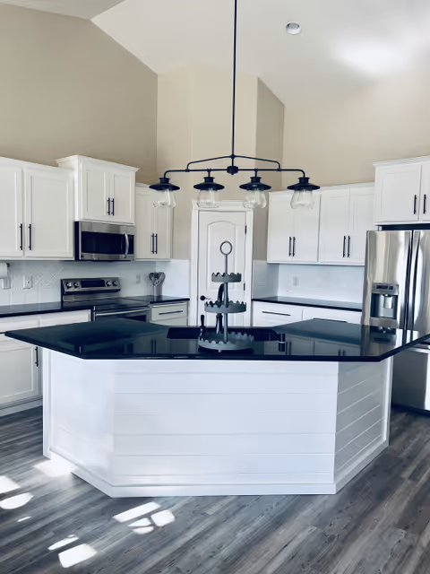 Bright white kitchen at Sunset Heights with island, pendant lights, and stainless appliances.