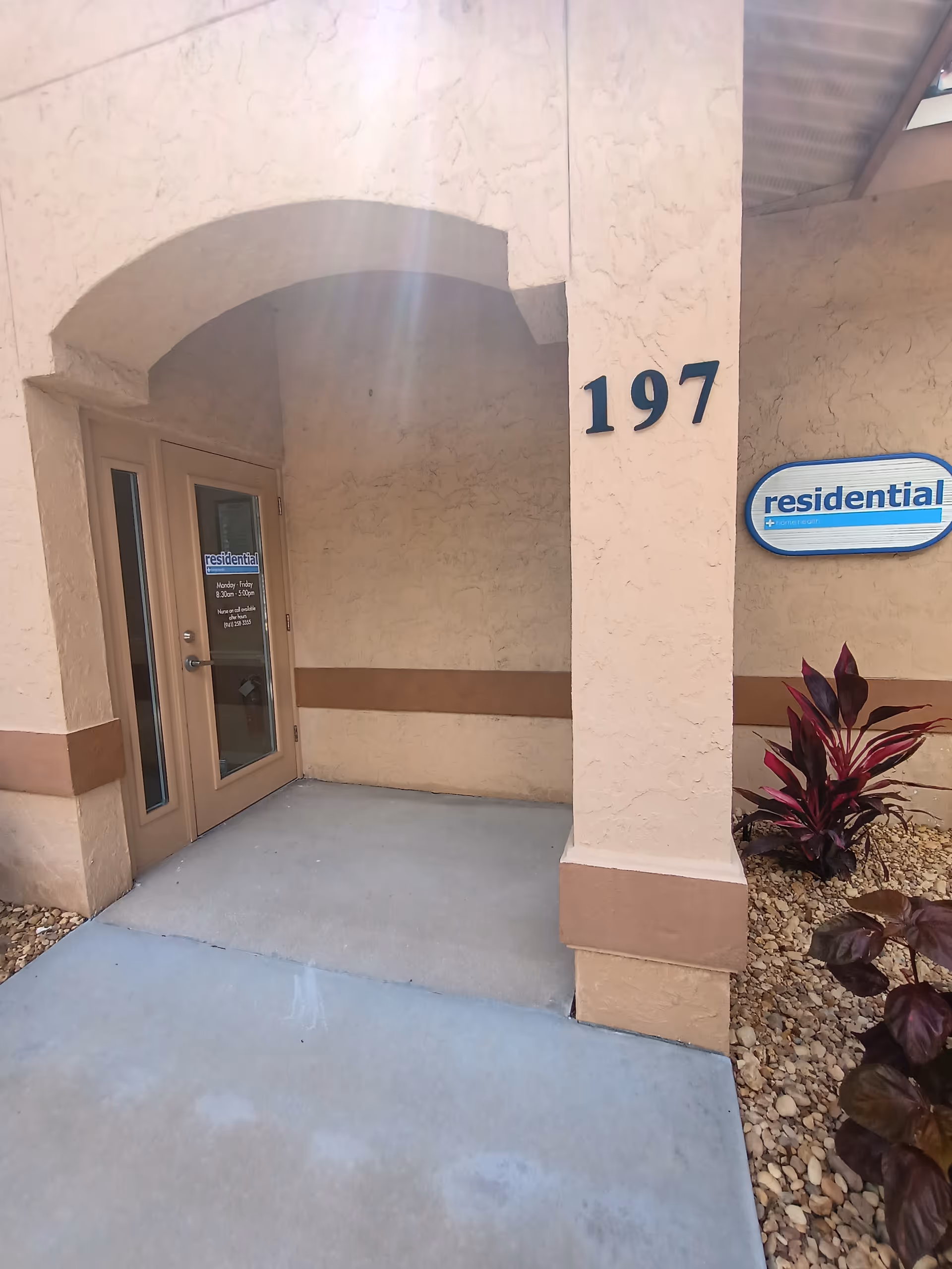 Exterior entrance of a senior facility with arched doorway and beige walls.