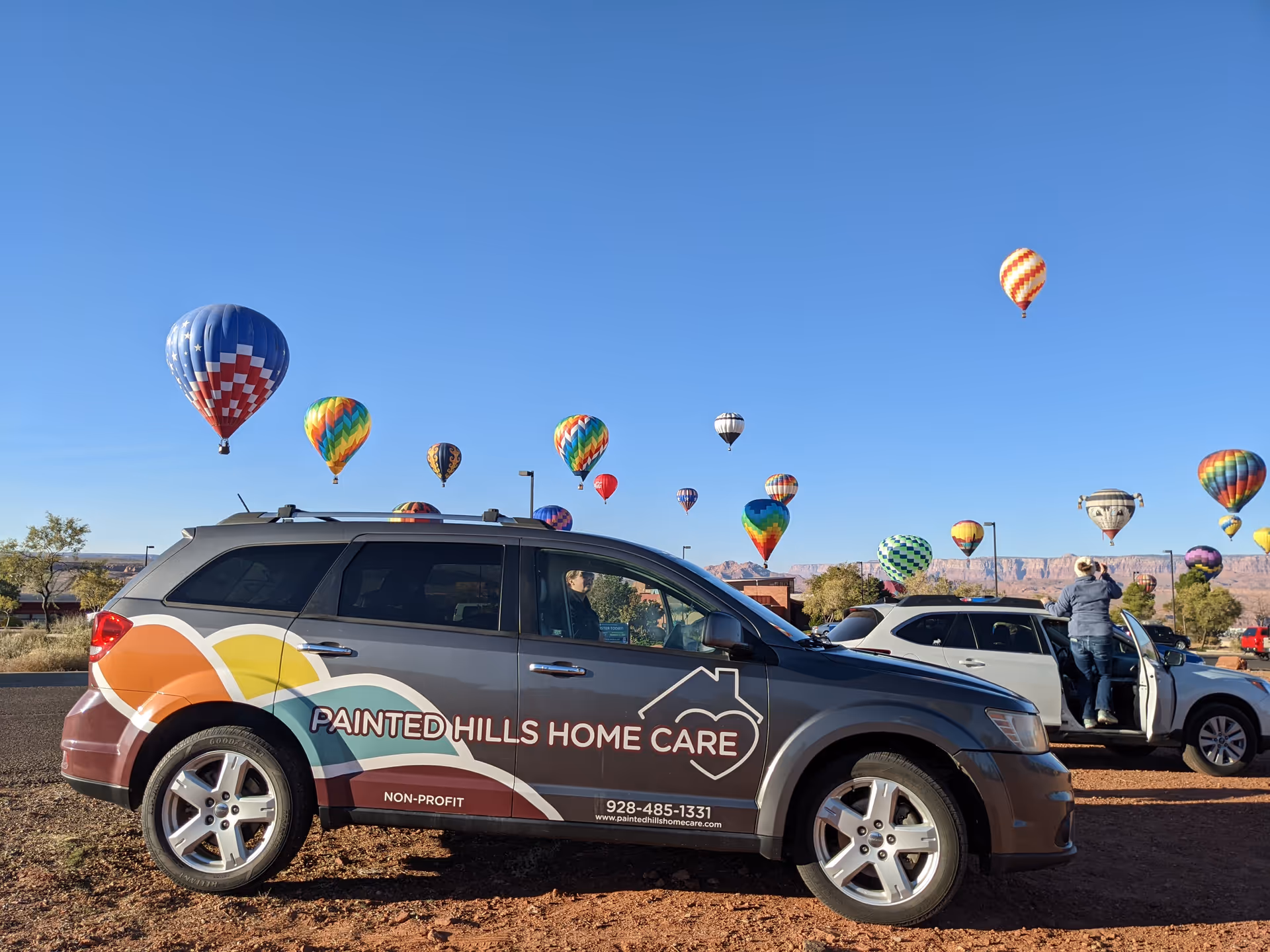 Branded Painted Hills Home Care van parked outdoors with balloons in a parking lot.