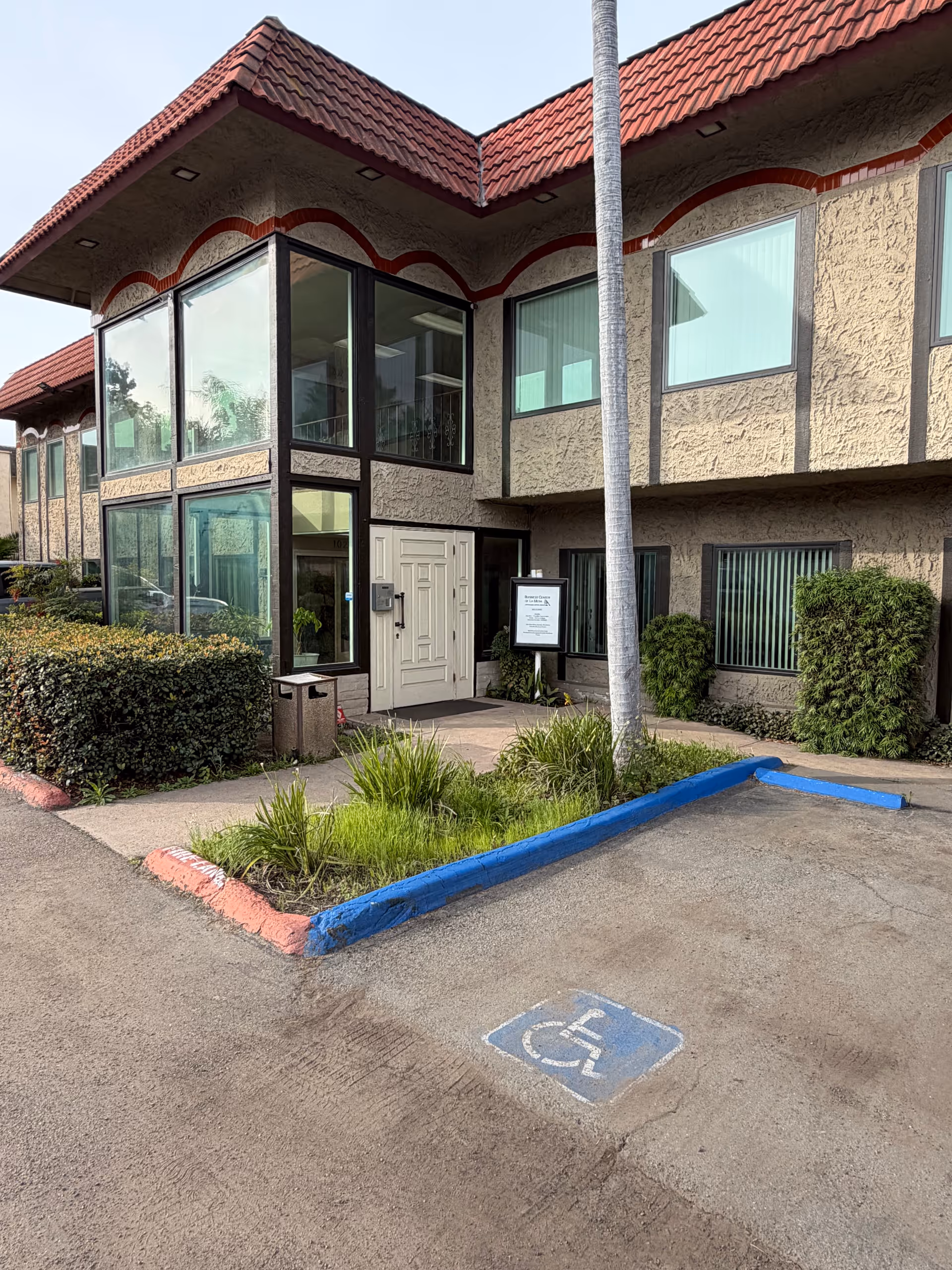 Front view of a senior living facility entrance with glass panels and landscaping.