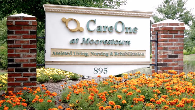 CareOne at Moorestown sign with brick pillars and colorful flowers in front.