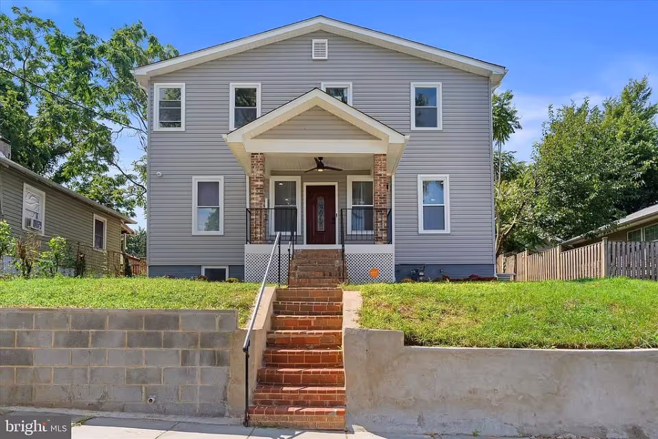 A two-story assisted living facility with a front porch and stairs leading up to the entrance.