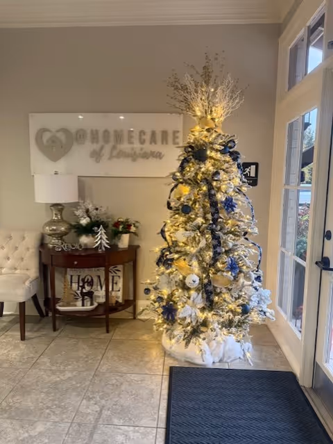 Lobby area with a white Christmas tree and a HomeCare of Louisiana sign.