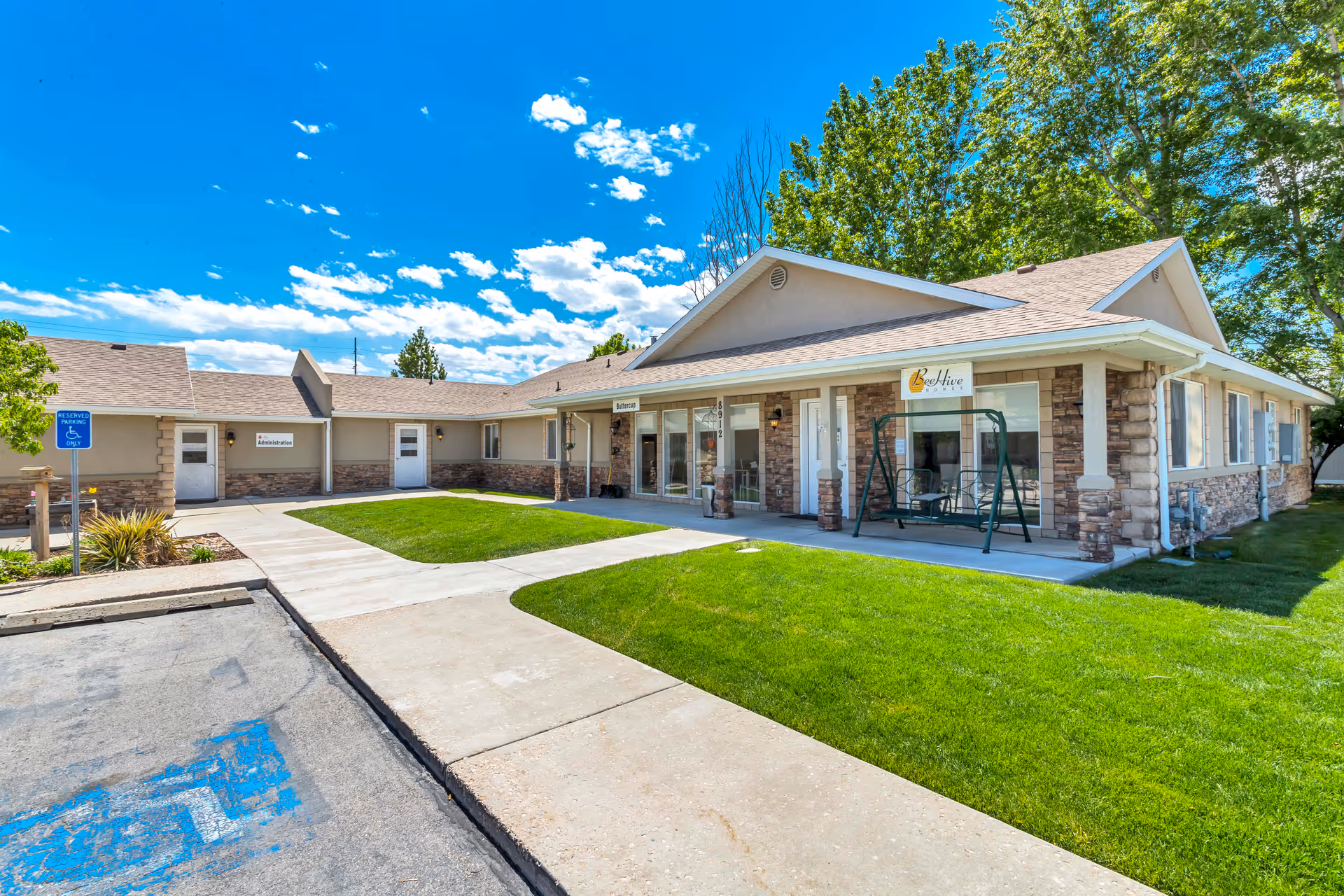 Single story senior living facility with stone accents, green lawn, and front entrance.
