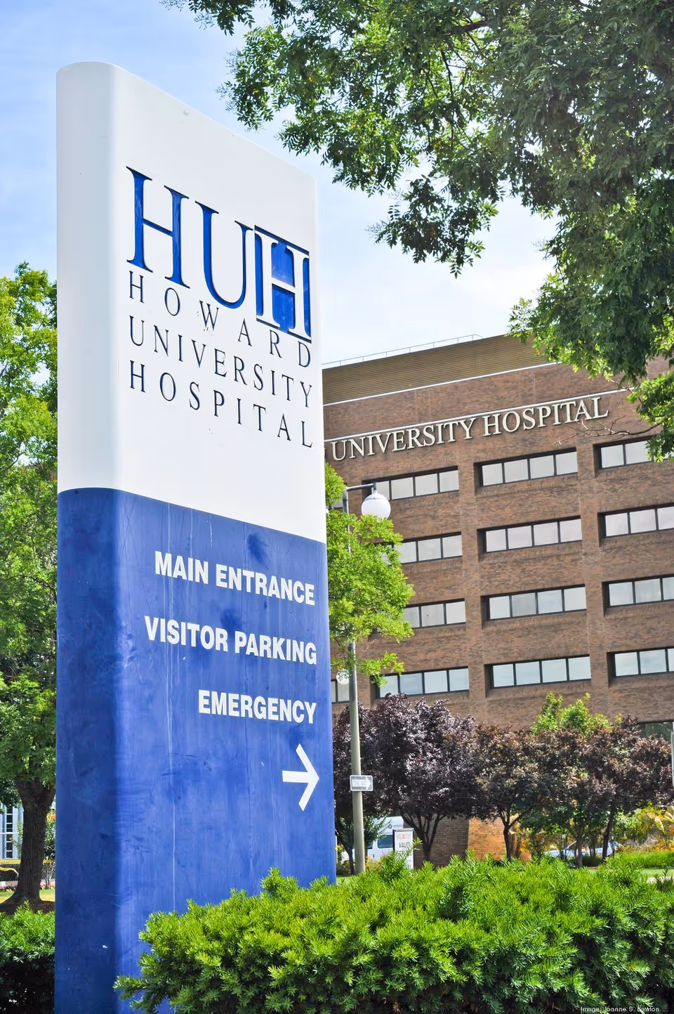 Tall outdoor sign for Howard University Hospital beside a brick building.