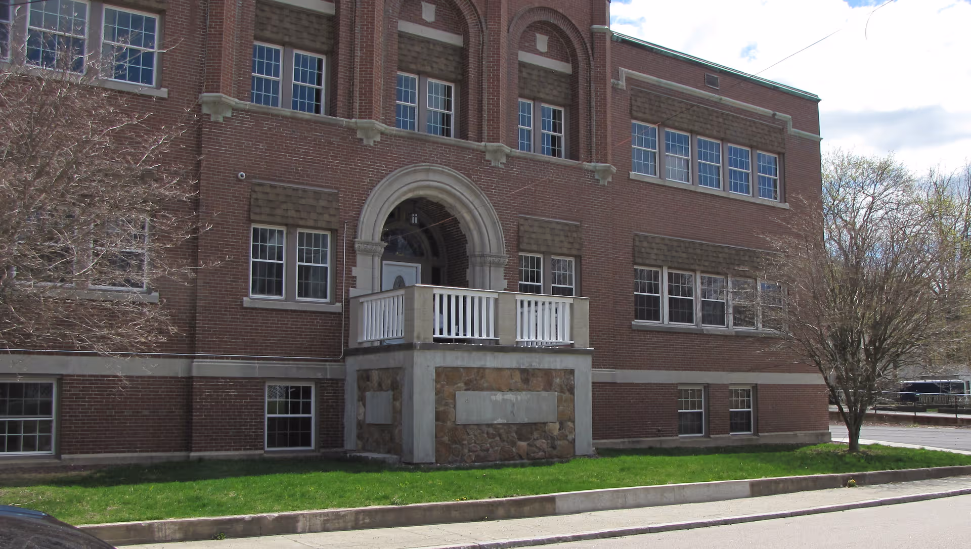 Brick two-story memory care facility with arched entrance and small front porch.
