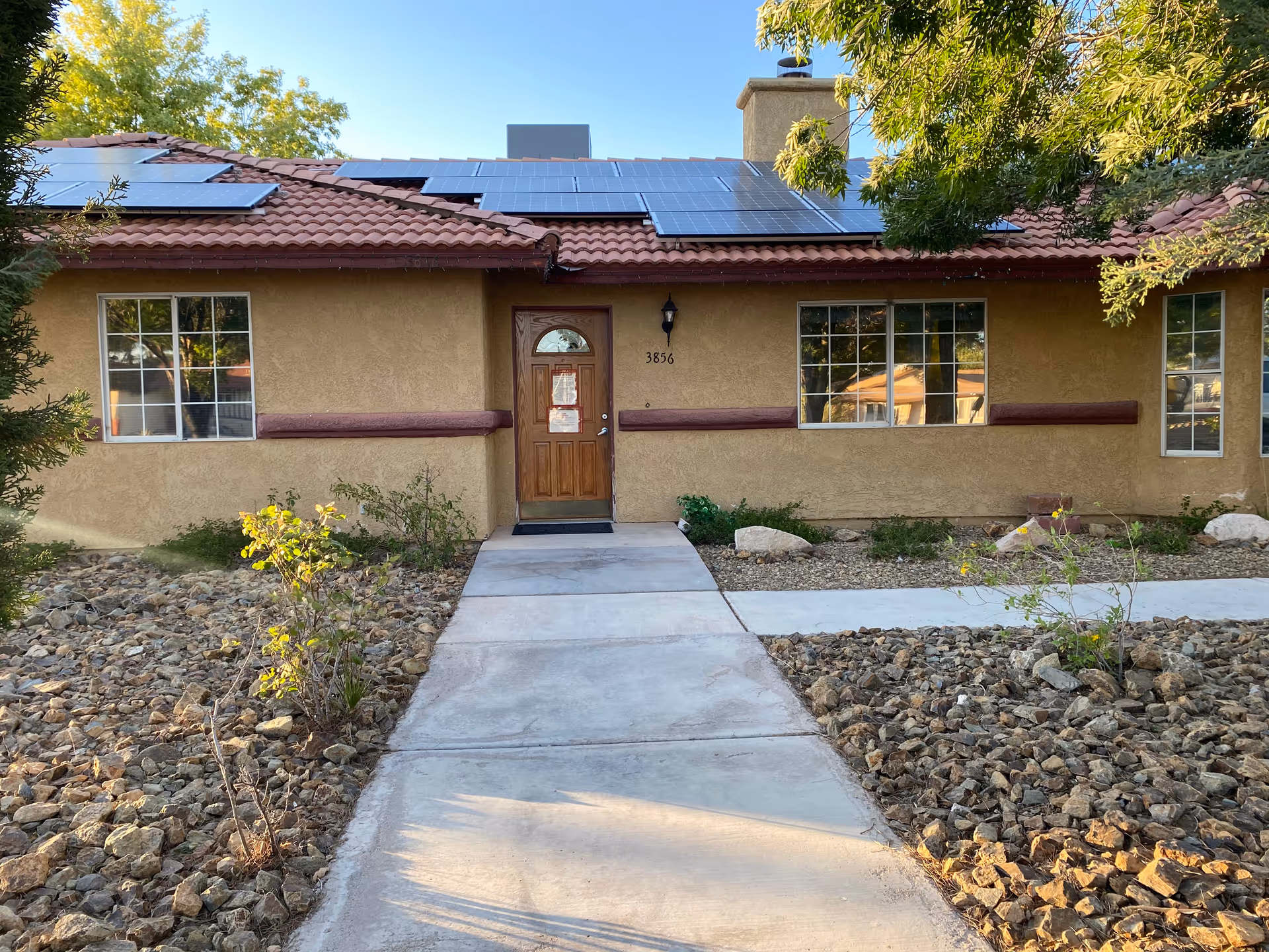 A single-story beige senior living facility with solar panels and a central doorway.