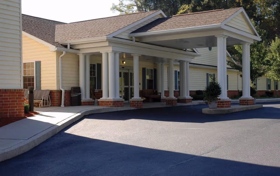Front view of Chestnut Knoll senior living facility entrance with columns and a covered driveway.