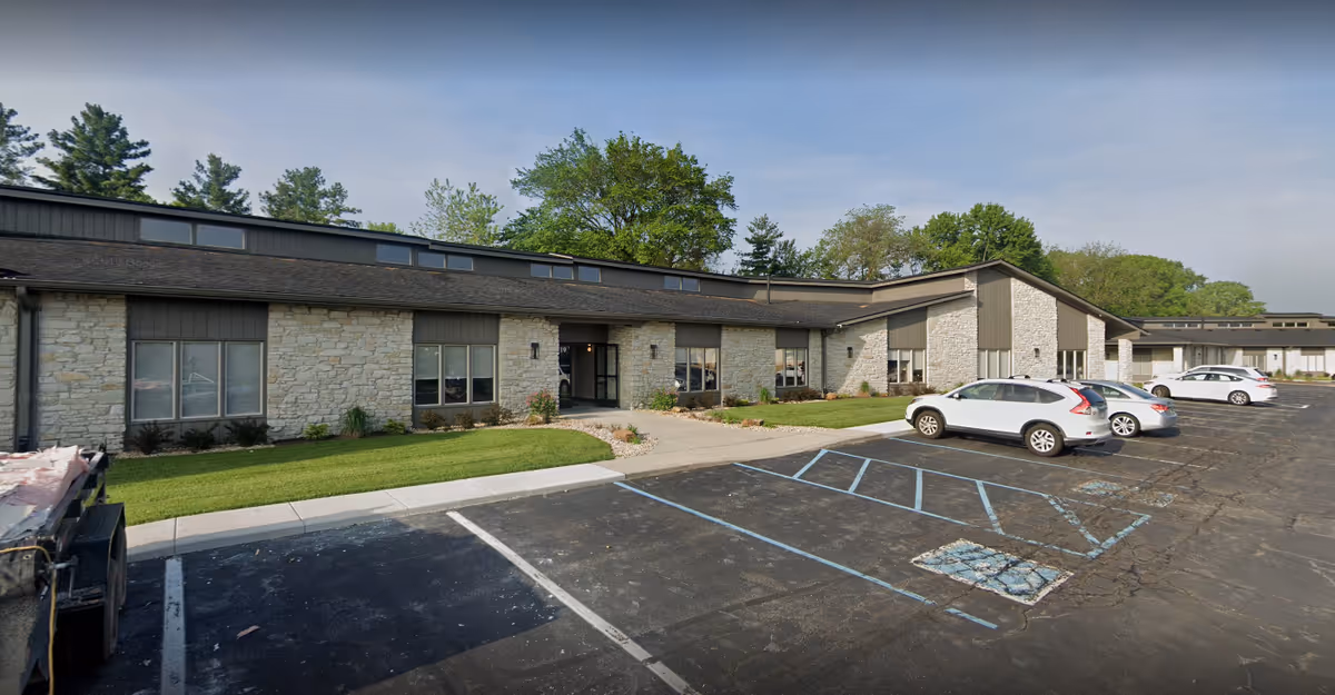 Front exterior of a single-story senior living facility with stone walls and a parking lot.