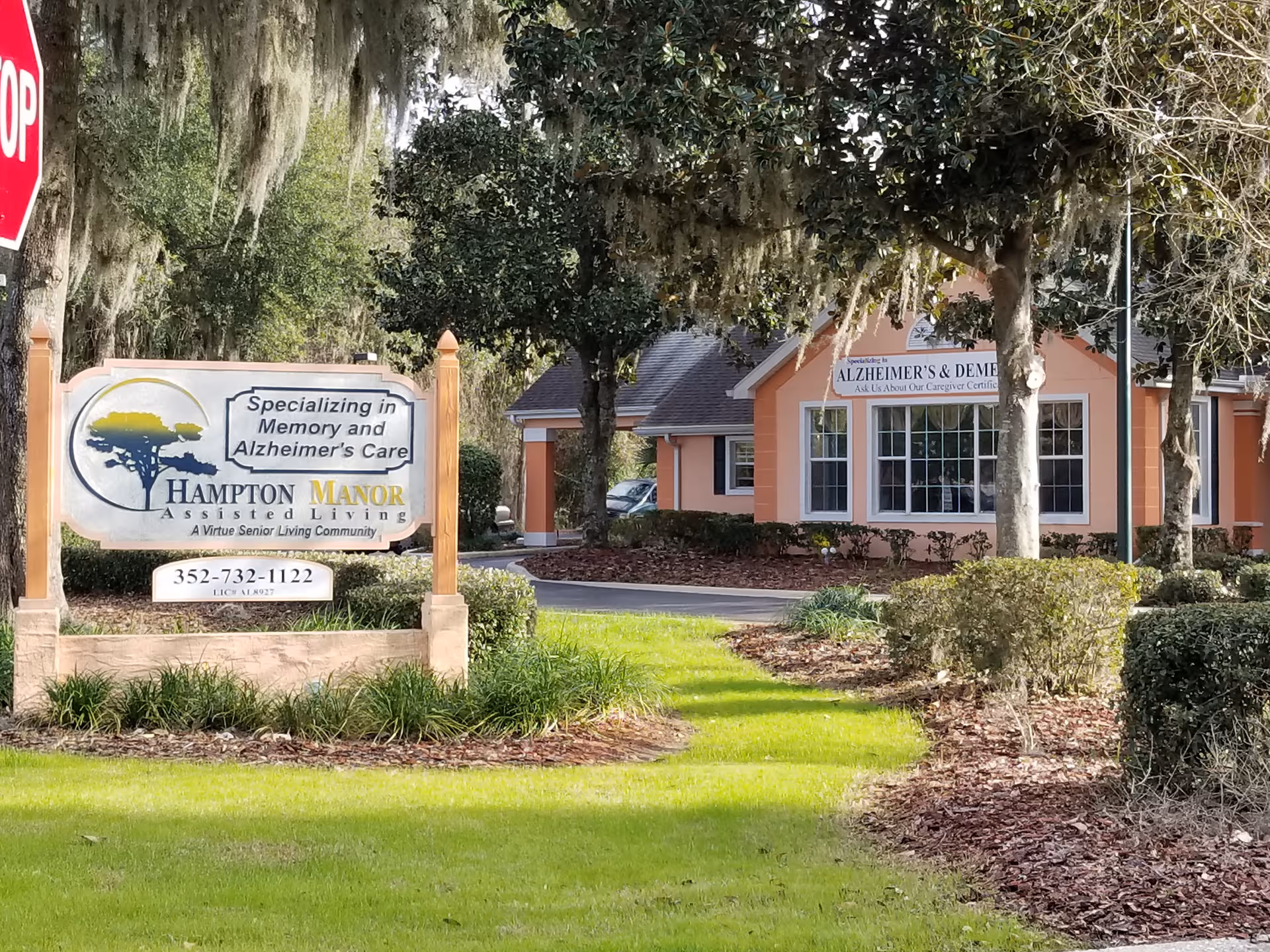 Orange building exterior with a Hampton Manor sign and landscaped lawn in foreground.