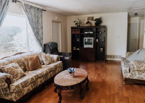 A cozy living room at Acorn Oaks Manor I with floral sofas and wooden floor.