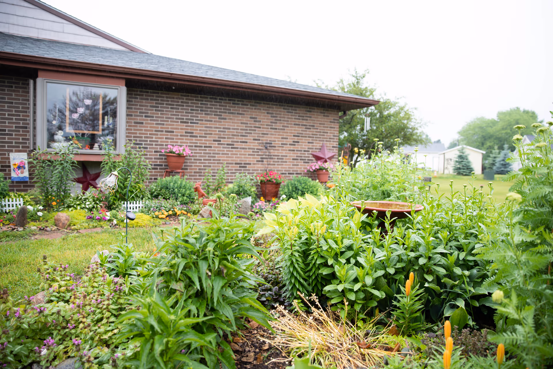 Avalon Village exterior: brick building with a lush front garden and potted flowers.