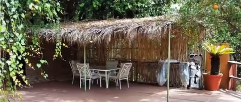 Outdoor patio at Bel Air Manor with a thatched shelter, table, and chairs.