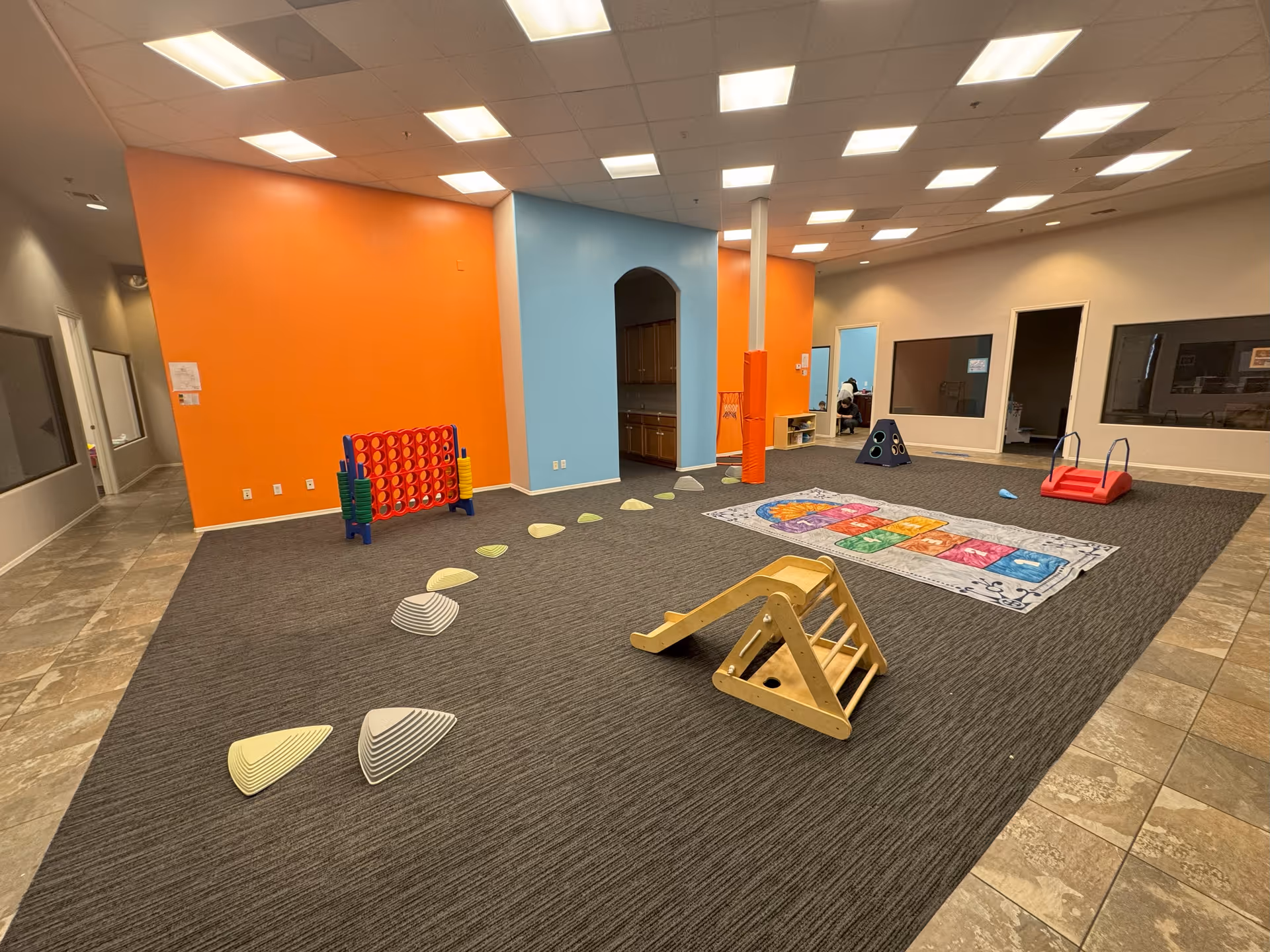 Colorful indoor play area with mats, a wooden ramp, and a colorful play mat.