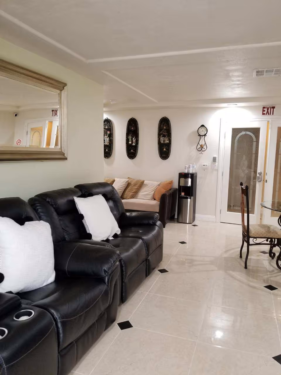 Leather sofas line a bright senior living lounge with a dining set and wall decor.
