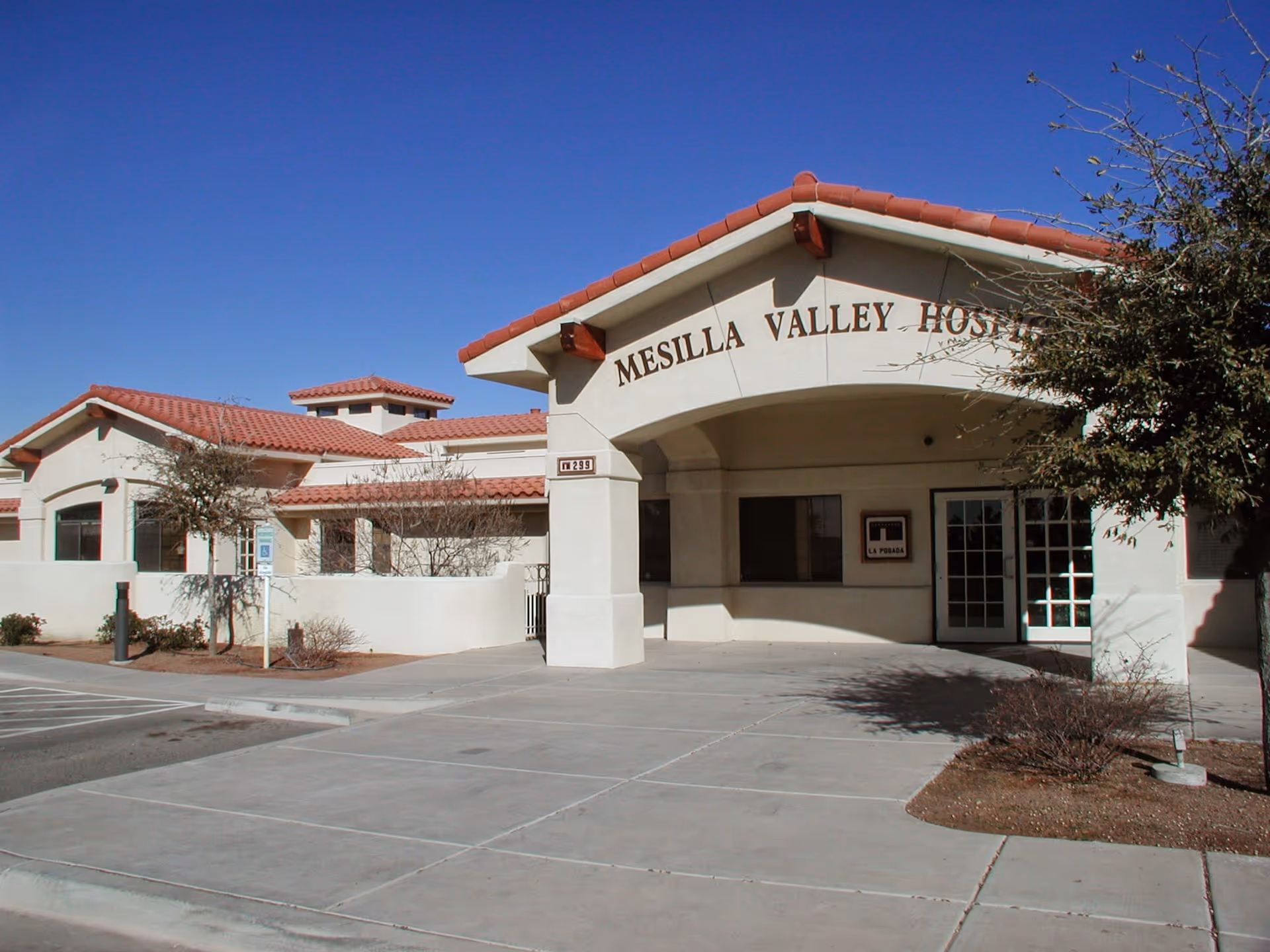 Exterior view of Mesilla Valley Hospice building with a curved entry and red tile roof.