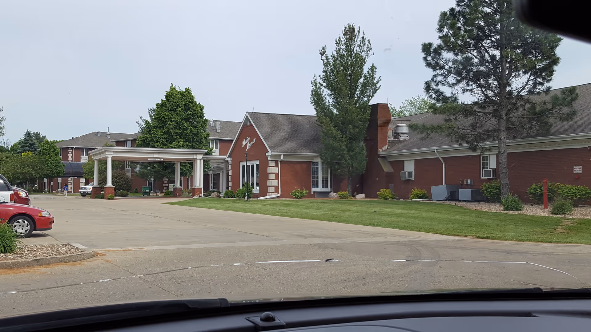 Brick senior living facility with a white portico entrance and green landscaping.