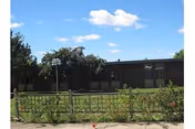 Front view of a single-story brick nursing home with a fenced yard.