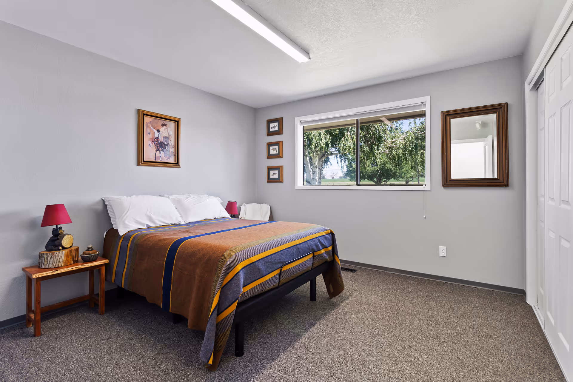A neatly made bedroom with a bed, a nightstand, and a window view.