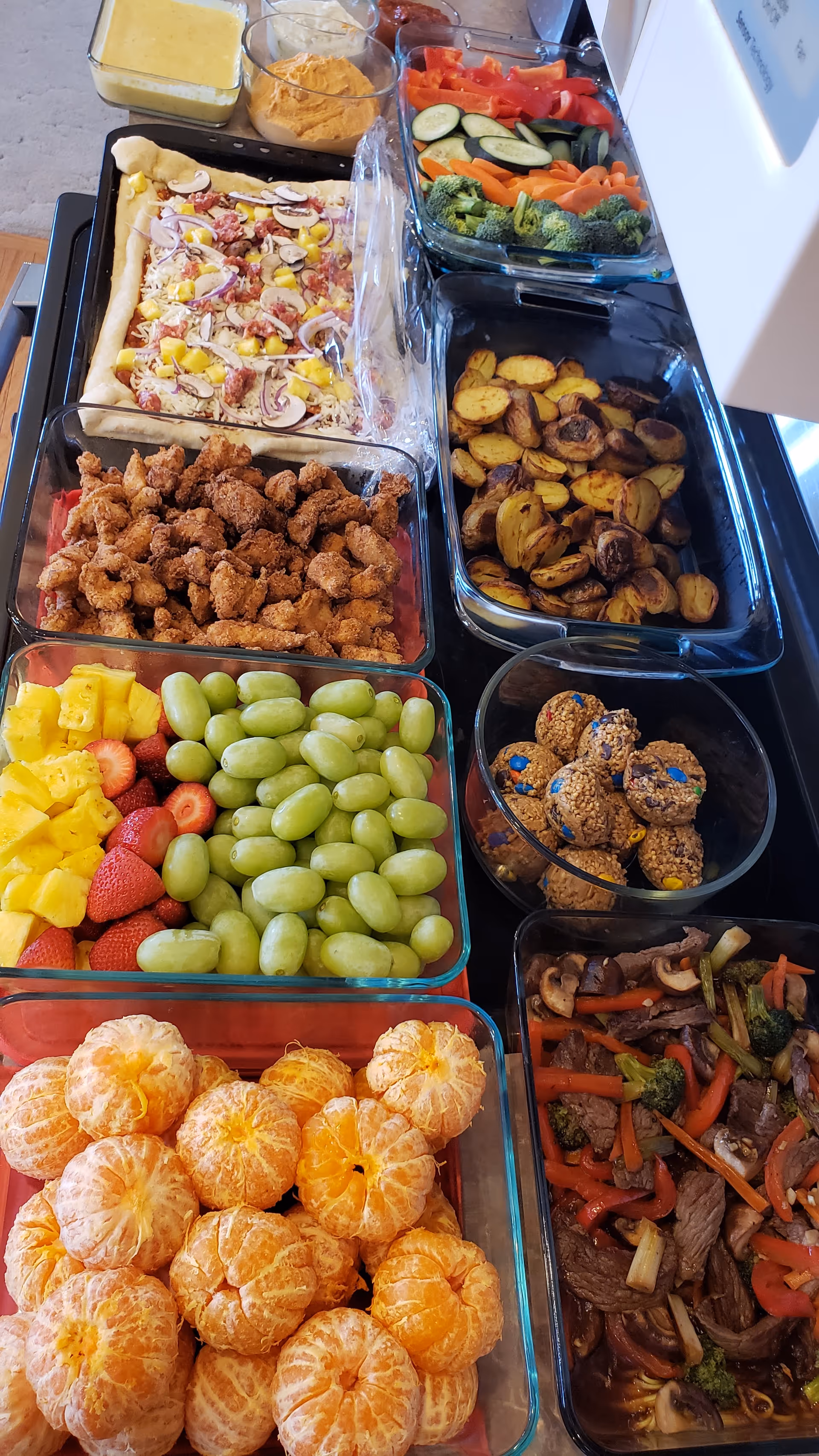 Assorted colorful food trays with fruits, vegetables, and dishes in a service line.