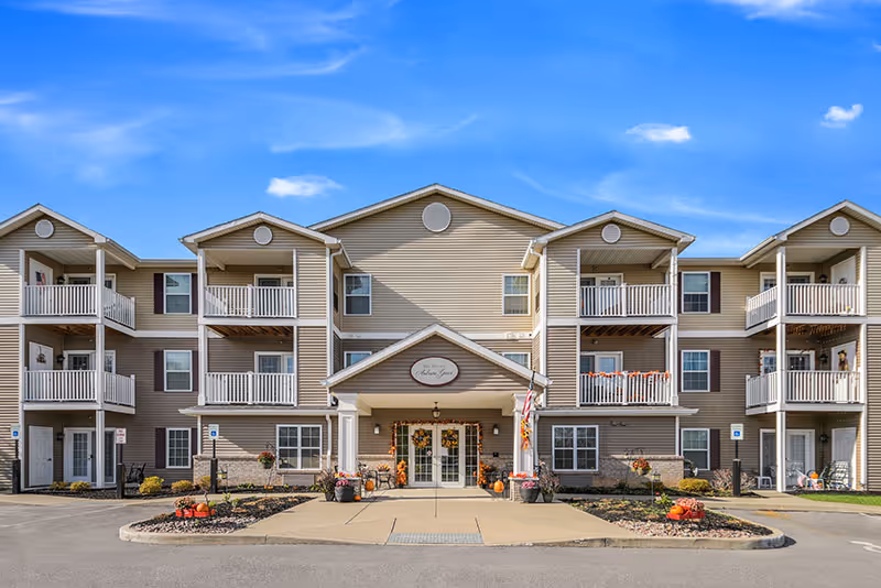 Beige multi-story senior living residence with balconies and a central entrance.