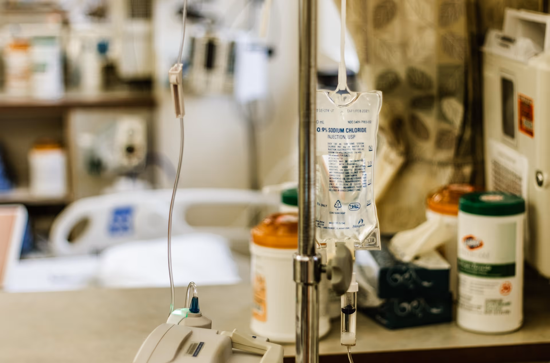 IV bag, tubing, and medical devices on a cart in a clinical interior.
