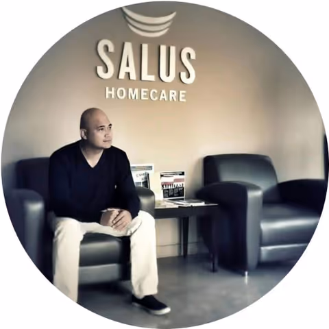 A man sits in a Salus Homecare lobby with chairs and magazines.