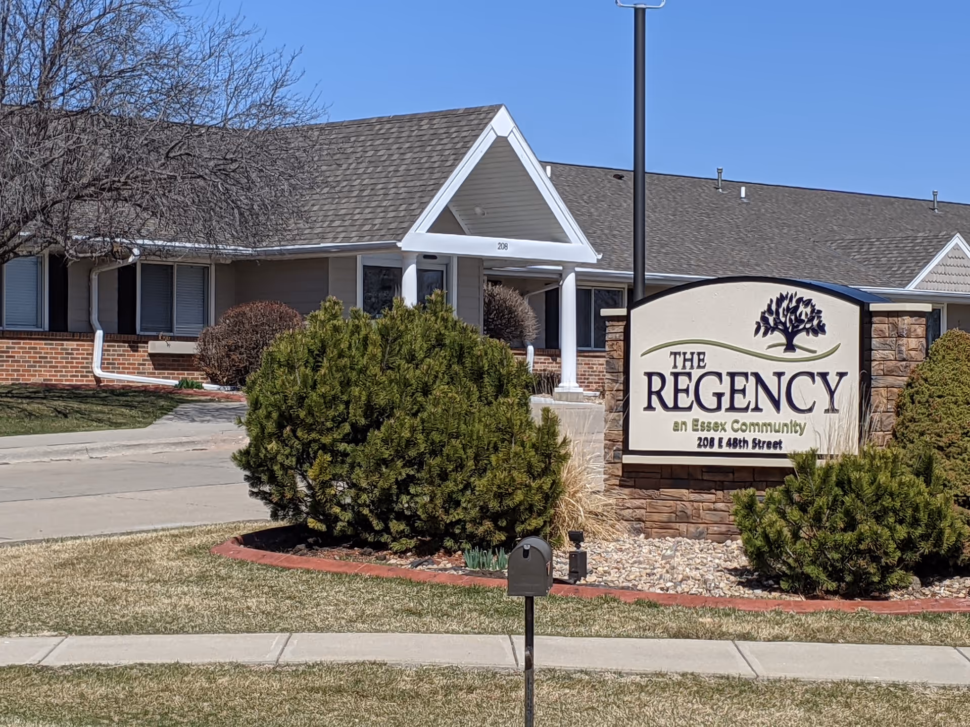 Front view of The Regency senior living facility with sign and landscaping.