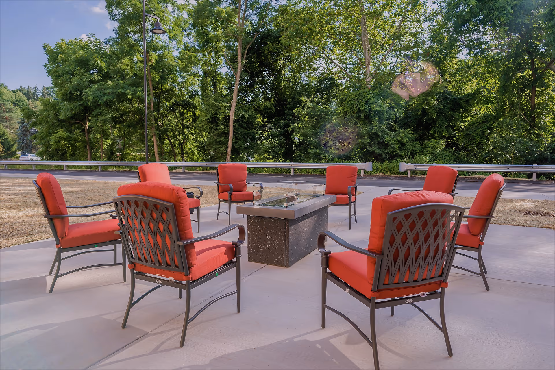 Outdoor seating area with red cushioned chairs around a central fire table.