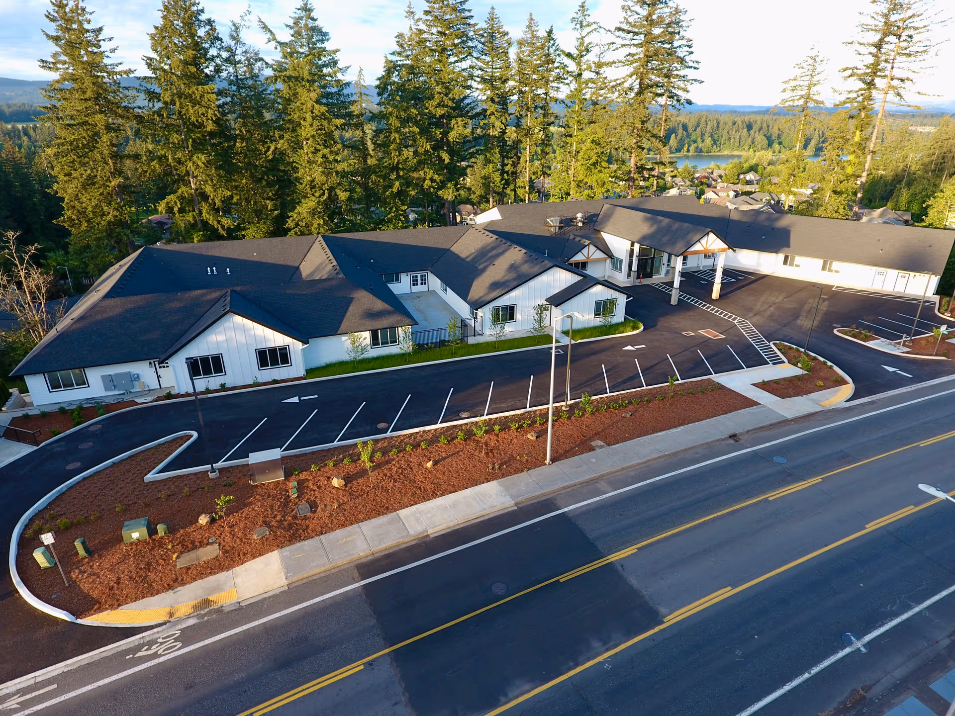 Aerial view of Lacamas Heights Memory Care with white buildings, dark roofs, and nearby trees.